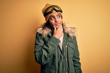 Young african american afro skier girl wearing snow sportswear and ski goggles Thinking worried about a question, concerned and nervous with hand on chin