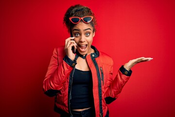 Young african american girl having conversation talking on the smartphone over red background very happy and excited, winner expression celebrating victory screaming with big smile and raised hands