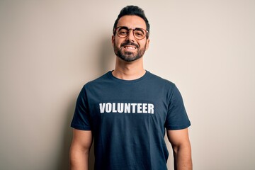 Handsome man with beard wearing t-shirt with volunteer message over white background with a happy and cool smile on face. Lucky person.
