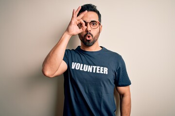 Handsome man with beard wearing t-shirt with volunteer message over white background doing ok...