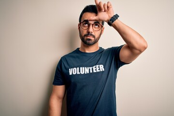 Handsome man with beard wearing t-shirt with volunteer message over white background making fun of...