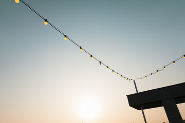 Outdoors wedding decoration with light bulbs at sunset.