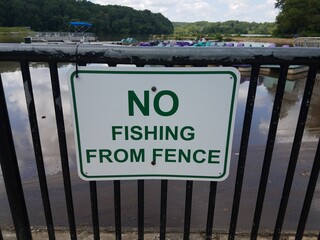 white no fishing from fence sign on metal fence near water