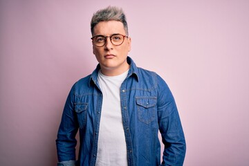 Fototapeta premium Young handsome modern man wearing glasses and denim jacket over pink isolated background Relaxed with serious expression on face. Simple and natural looking at the camera.