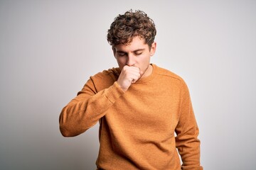 Young blond handsome man with curly hair wearing casual sweater over white background feeling...