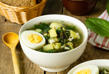 Green soup with sorrel, eggs and potatoes on a wooden background