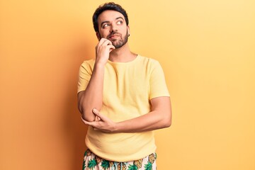 Young hispanic man wearing swimwear thinking concentrated about doubt with finger on chin and...