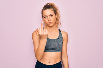 Young beautiful blonde sportswoman with blue eyes doing exercise wearing sportswear Showing middle finger, impolite and rude fuck off expression