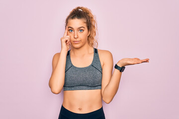 Young beautiful blonde sportswoman with blue eyes doing exercise wearing sportswear confused and...