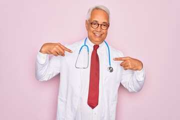 Middle age senior grey-haired doctor man wearing stethoscope and professional medical coat looking confident with smile on face, pointing oneself with fingers proud and happy.