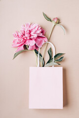 Beautiful pink peony in paper bag with place for text. Sale, shopping and eco-friendly packaging concept