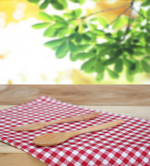 spoon with fork on checkered tablecloth and blur leaves background
