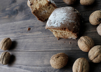 Fresh homemade baking on an old wooden table near walnuts. A piece of cake on a wooden board.
