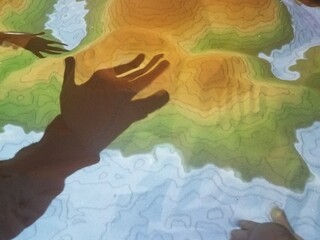 shadows of hands on sand hills with contour lines