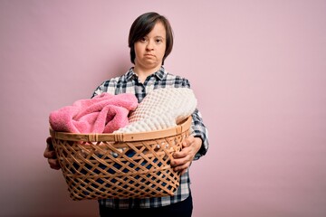 Young down syndrome woman doing housework domestic chores holding laundry wicker basket with a...