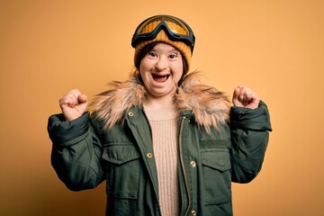 Young down syndrome woman wearing ski coat and glasses for winter weather celebrating surprised and amazed for success with arms raised and open eyes. Winner concept.