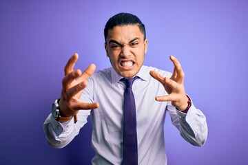 Young brazilian businessman wearing elegant tie standing over isolated purple background Shouting frustrated with rage, hands trying to strangle, yelling mad