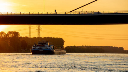 Rheinschiff unter Leverkusener Brücke bei Sonnenuntergang