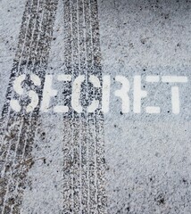 secret sign on black asphalt with tire tracks and white snow