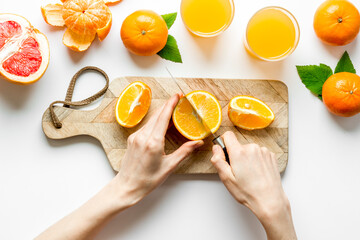 Hands cutting citrus fruit on board top view