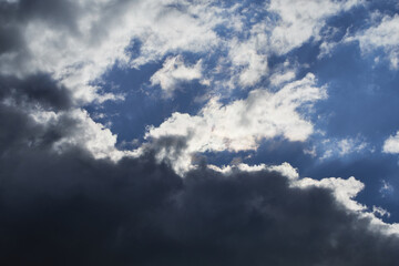 Fototapeta premium Overcast blue sky with dark cumulus clouds on a sunny day