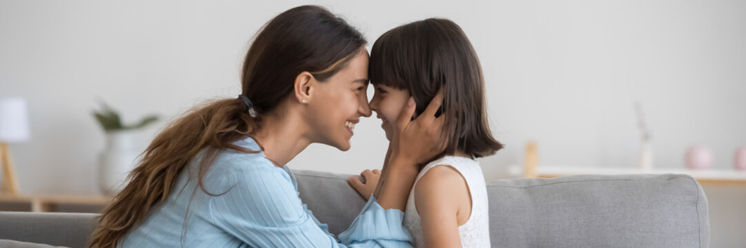 Horizontal photo banner for website header design loving mother seated on couch touching noses face with adorable little daughter. Happy motherhood, cherish, family bond and unconditional love concept