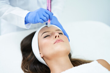 Naklejka premium Beautiful young woman getting face treatment at beauty salon.