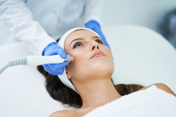 Beautiful young woman getting face treatment at beauty salon.