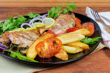 Baked ocean perches with vegetables on black dish close-up