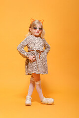 funny girl in leopard dress and glasses on yellow background posing