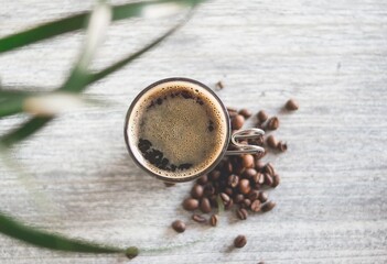 High angle closeup shot of a cup of coffee and coffee beans