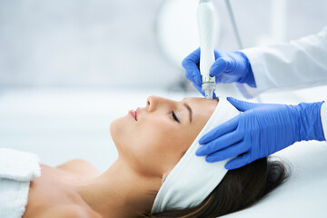 Beautiful young woman getting face treatment at beauty salon.