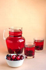 Fresh summer drink, homemade compote juice with sweet cherry on a beige background with copy space.