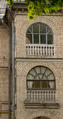 Arched windows on the facade of a residential white brick apartment building. Old windows with wooden frames with railing, small columns. The courtyard of an old apartment building in Europe.