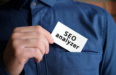 Seo analyzer text on a white sign in the hand of a man in shirt