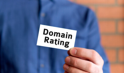 A man in a blue shirt holds a sign with the text of Domain rating in one hand