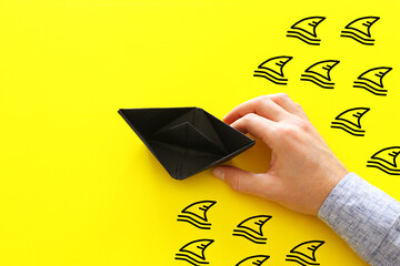 concept banner of avoiding crisis. paper boat escaping sharks idea
