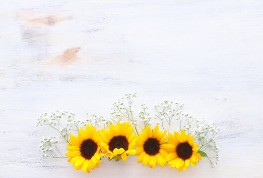 Top view image of sunflowers over white wooden background