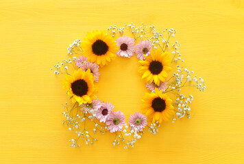 Top view image of sunflowers over yellow wooden background