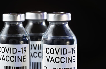 Coronavirus Covid-19 vaccine concept -  three glass vials on black table, closeup detail (own design - dummy barcode, not real product)