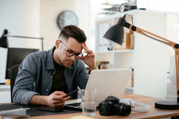 Young businessman using laptop in his office. Businessman working and taking notes.
