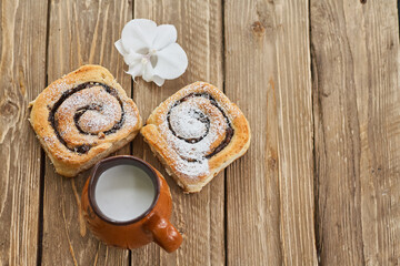 Basket of homemade buns with jam, served on old wooden table with cup of milk