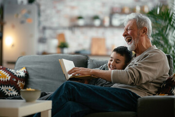 Grandfather and grandson reading a book. Grandpa and grandson enjoying at home.	