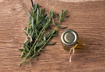 Top view Bottle glass of essential rosemary oil with rosemary branch on wooden rustic background.