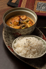 shrimp with curry on a bowl and rice on a leather mat wodden table