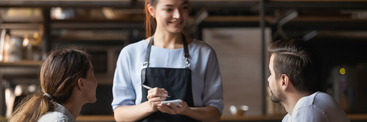 Courteous waitress, small business owner holding notepad ready take restaurant visitors order couple. Eating in public places, good service concept. Horizontal photo banner for website header design