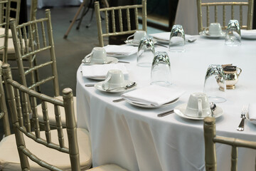 A glass of clear water ,cup ,spoon ,fork and dish is upside down  on the dining table covered with elegant white cloth.