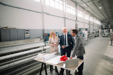  Colleagues working on project. Team of architects discussing business in factory.