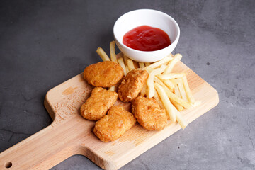 Nugget, french fries plating on wood chopping board
