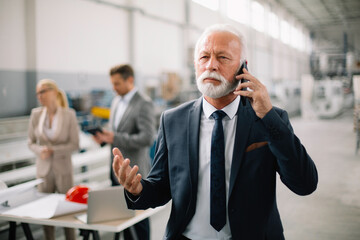 Portrait of handsome businessman. Man talking to the phone in factory.